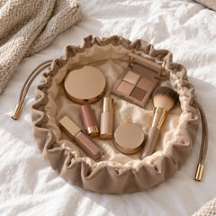 Taupe lay-flat makeup bag opened flat with makeup on a bed